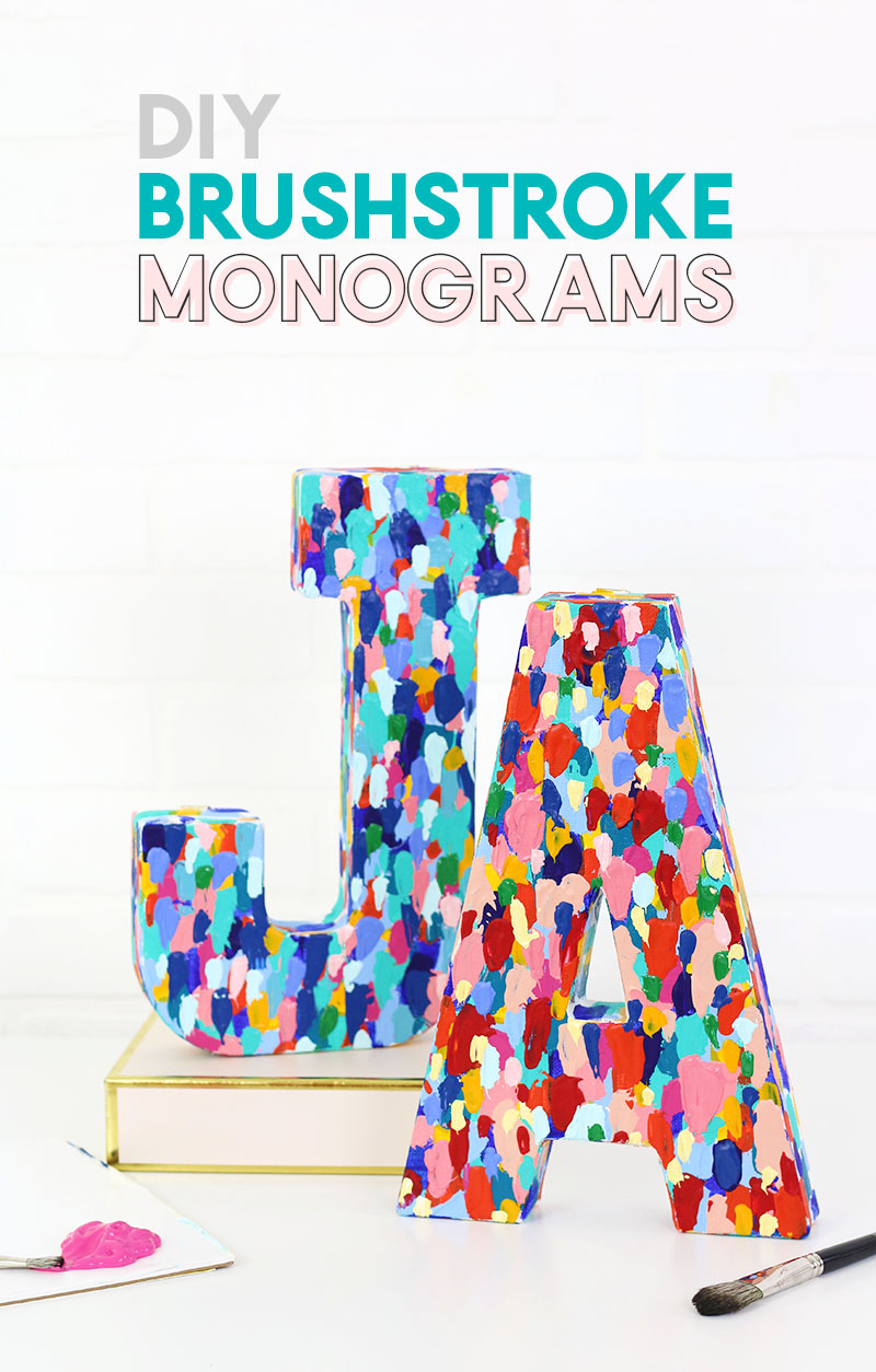 Paper mache letters J and A covered in multicolor brushstroke paint dabs, on a gold book beside a paintbrush