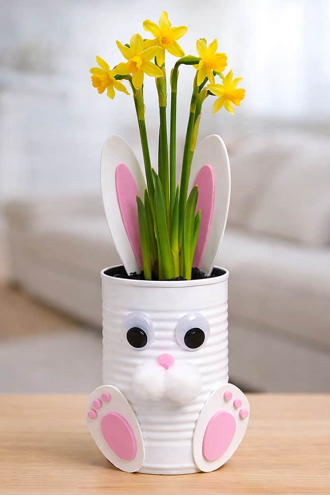 White tin can bunny planter with pink and white foam ears, pom pom cheeks, googly eyes and yellow daffodils inside