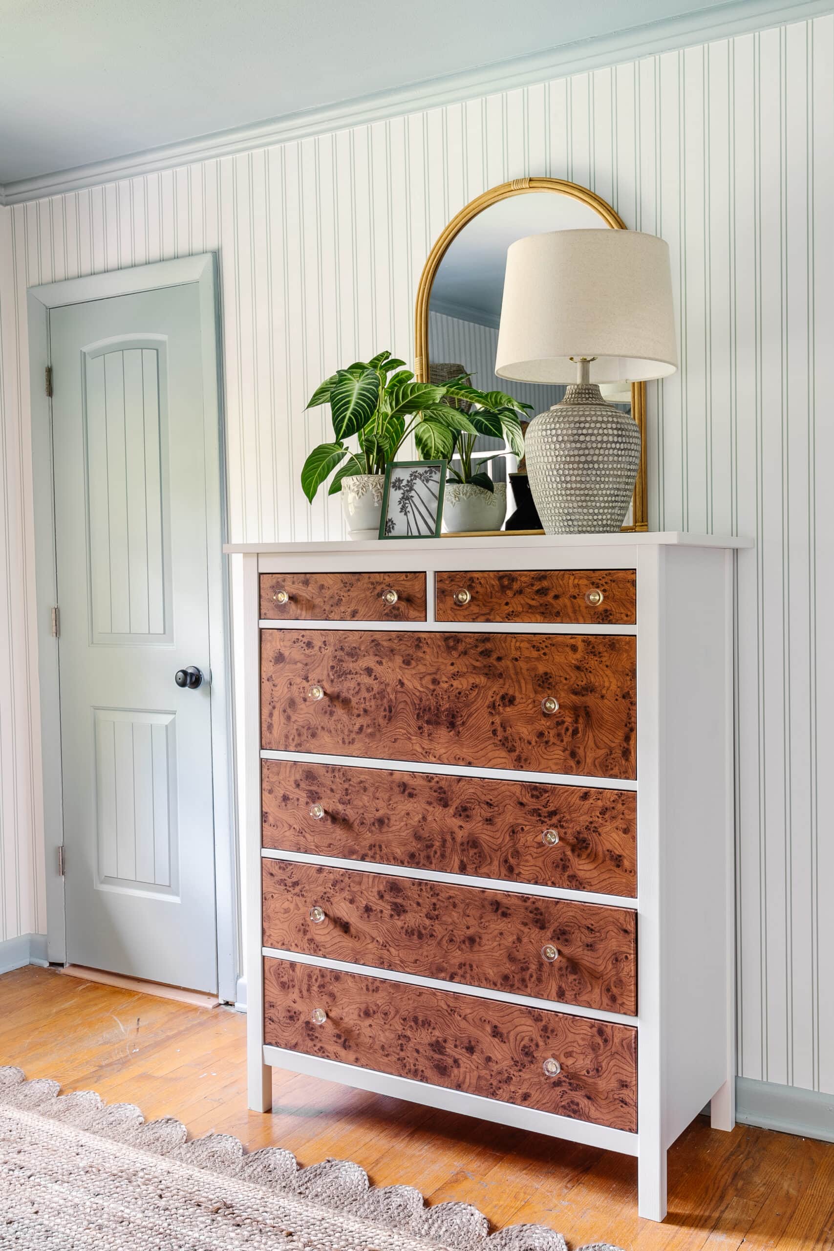 Burl Wood IKEA Dresser Hack | IKEA Bedroom Hack White IKEA Hemnes dresser with burl wood contact paper drawer fronts and glass knobs, styled with a lamp, plant and mirror