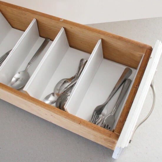 Custom white silverware drawer organizer with tall dividers holding spoons and forks in an open wood drawer