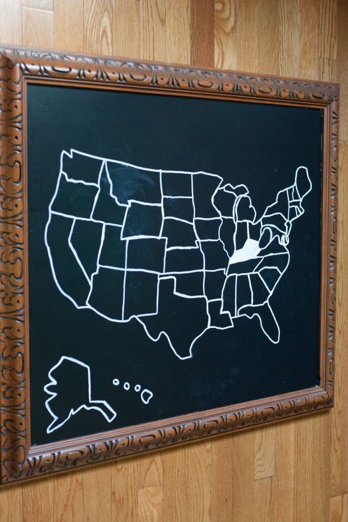 Ornate carved wood frame holding a black chalkboard painted glass with a white chalk outline map of the United States
