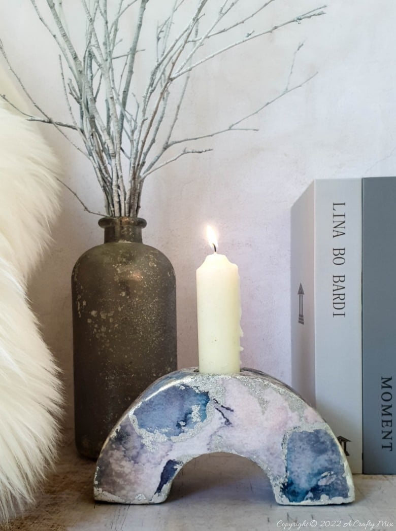Concrete Arch Candle Holder | Cardboard Mold DIY Arched concrete candle holder with blue and silver marbled decoupage holding a white pillar candle beside books