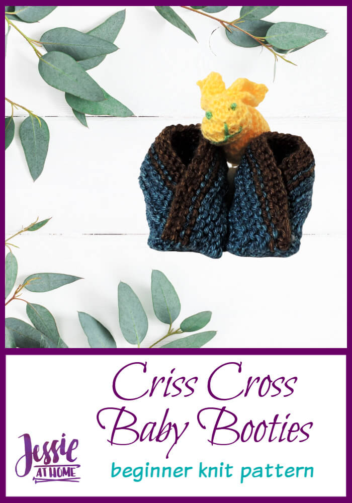 Pair of brown and blue knit criss cross baby booties with a yellow toy dinosaur, framed by eucalyptus with a pattern title
