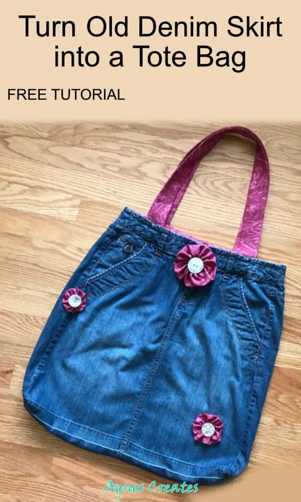 Upcycled denim skirt tote bag with front pockets, pink paisley straps and three magenta yo-yo flowers with white buttons