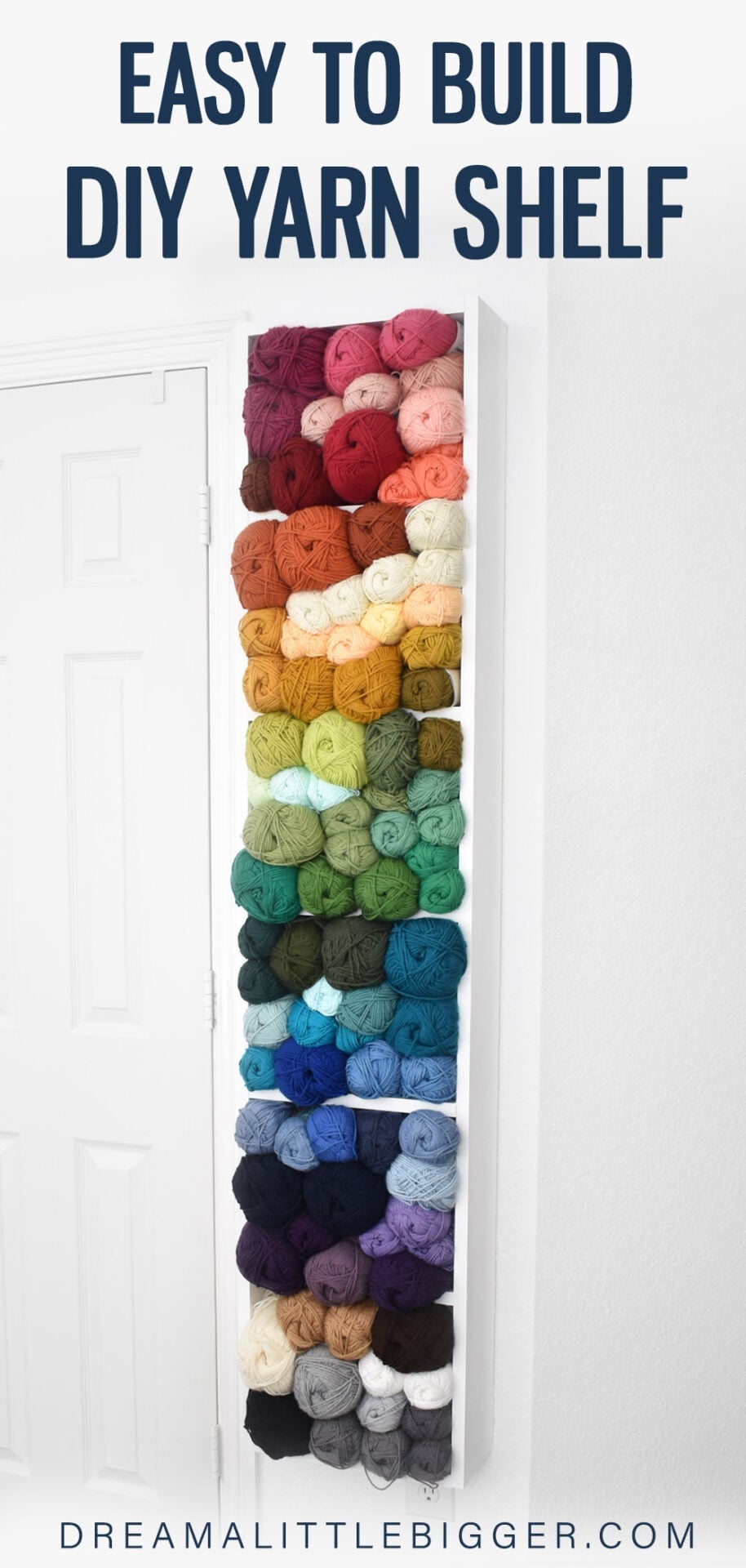 Tall white wall-mounted yarn shelf beside a door, filled with skeins of yarn sorted in rainbow order from red down to black
