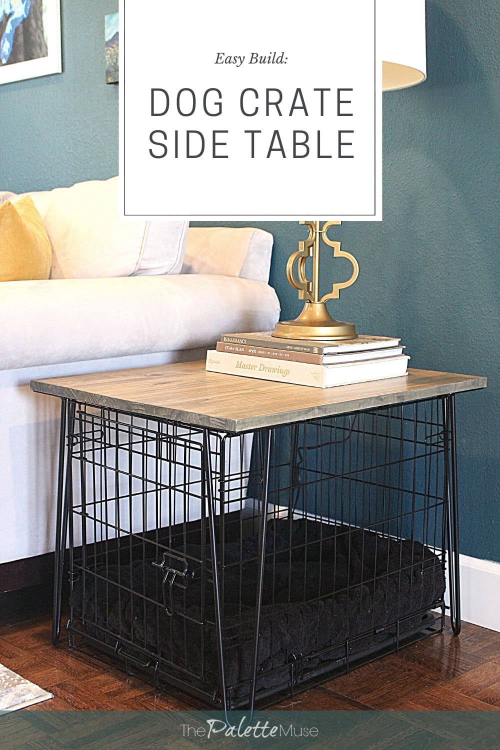 Dog crate side table with a wood plank top on black wire hairpin legs beside a white sofa, topped with books and a lamp