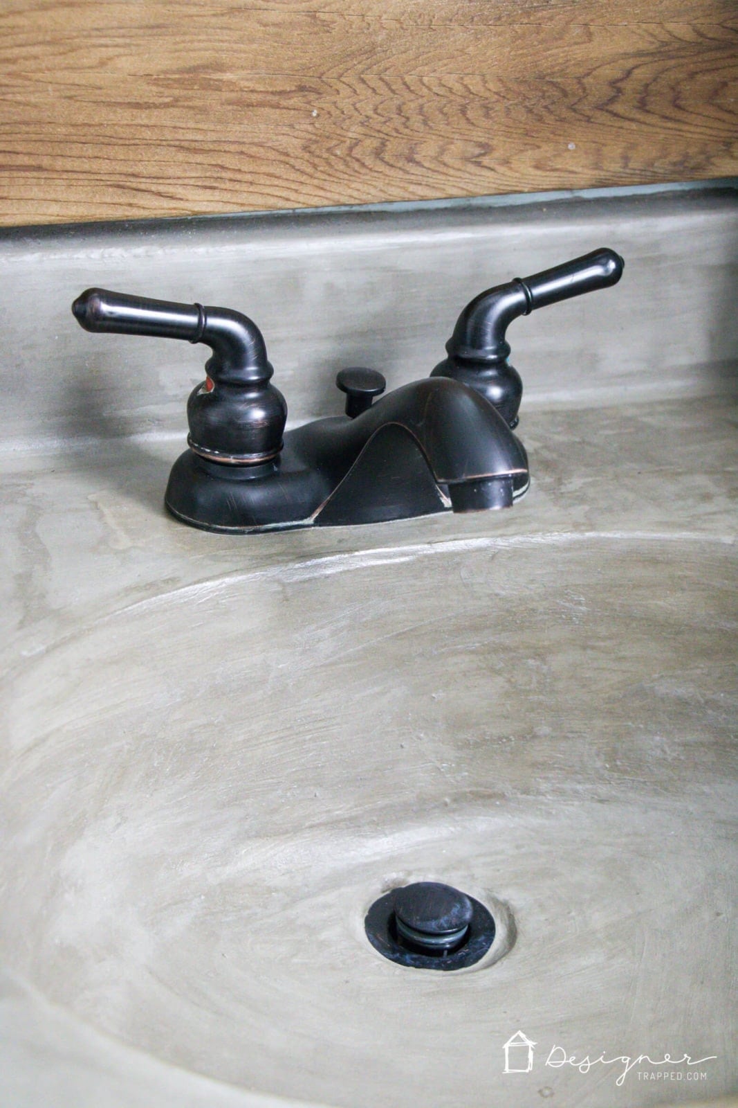 DIY Concrete Vanity and Sink | Overlay Makeover Close view of a smooth gray concrete overlay bathroom sink and vanity top with an oil rubbed bronze faucet and drain