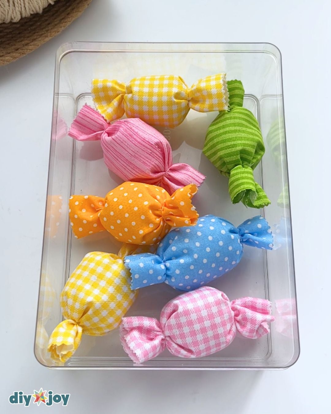 Loose no-sew fabric candies in gingham, stripe and polka dot prints piled in a clear acrylic tray as table decor
