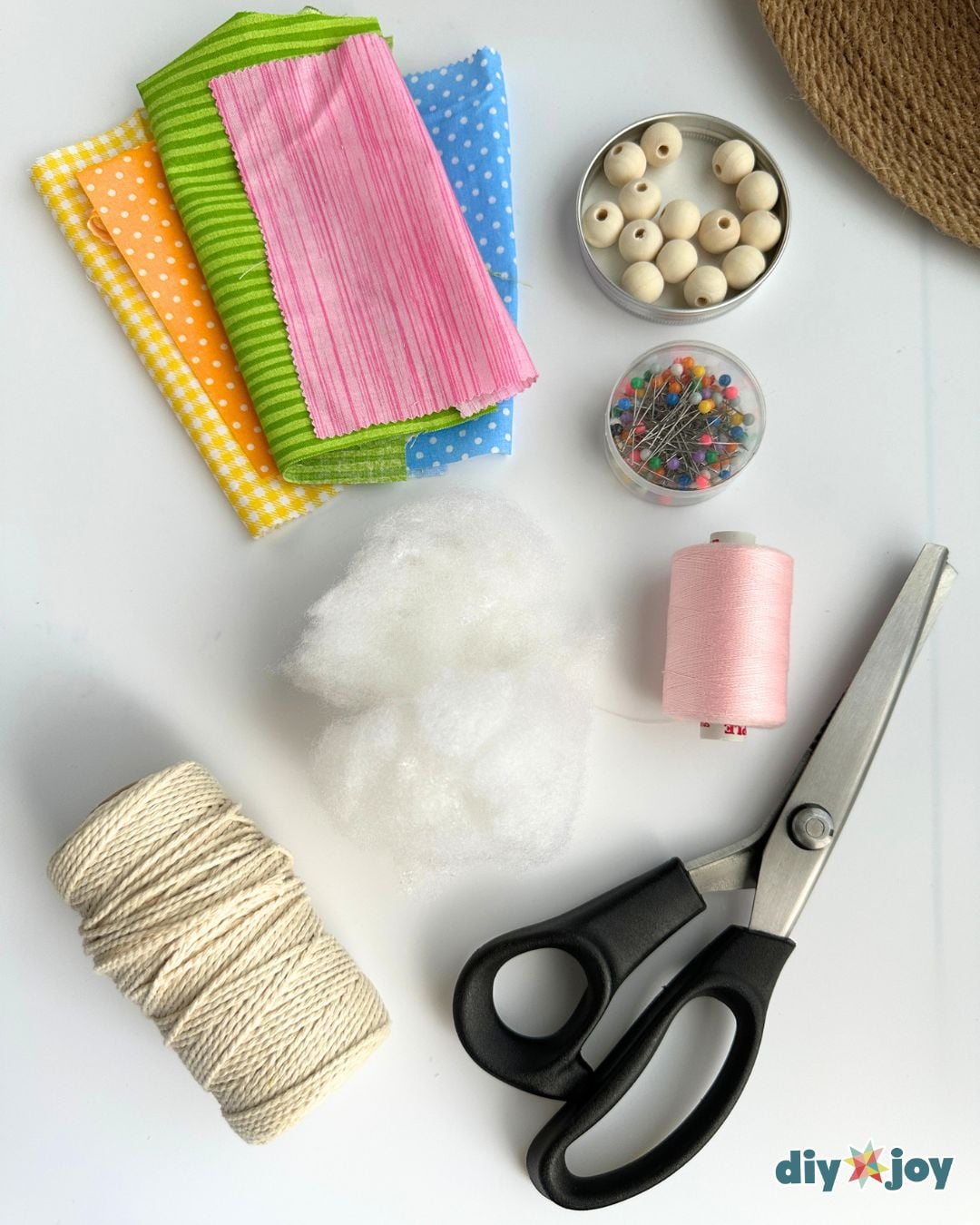 DIY candy garland supplies: fabric scraps, fiberfill, cotton twine, pink thread, pins, wooden beads and pinking shears