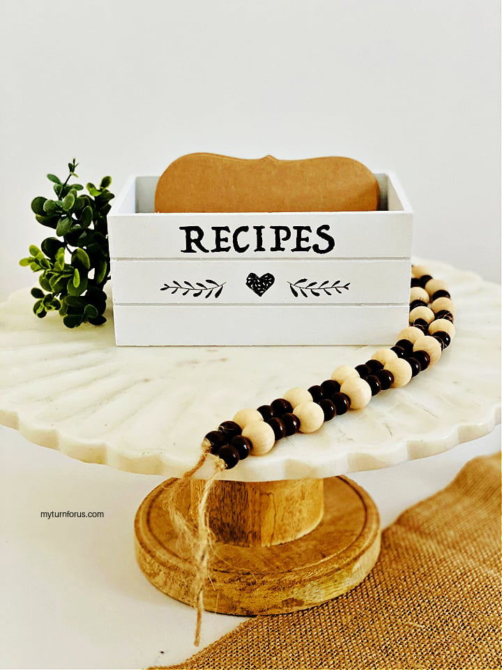 Farmhouse recipe box, white crate with black RECIPES lettering and leaves on a marble cake stand with beads