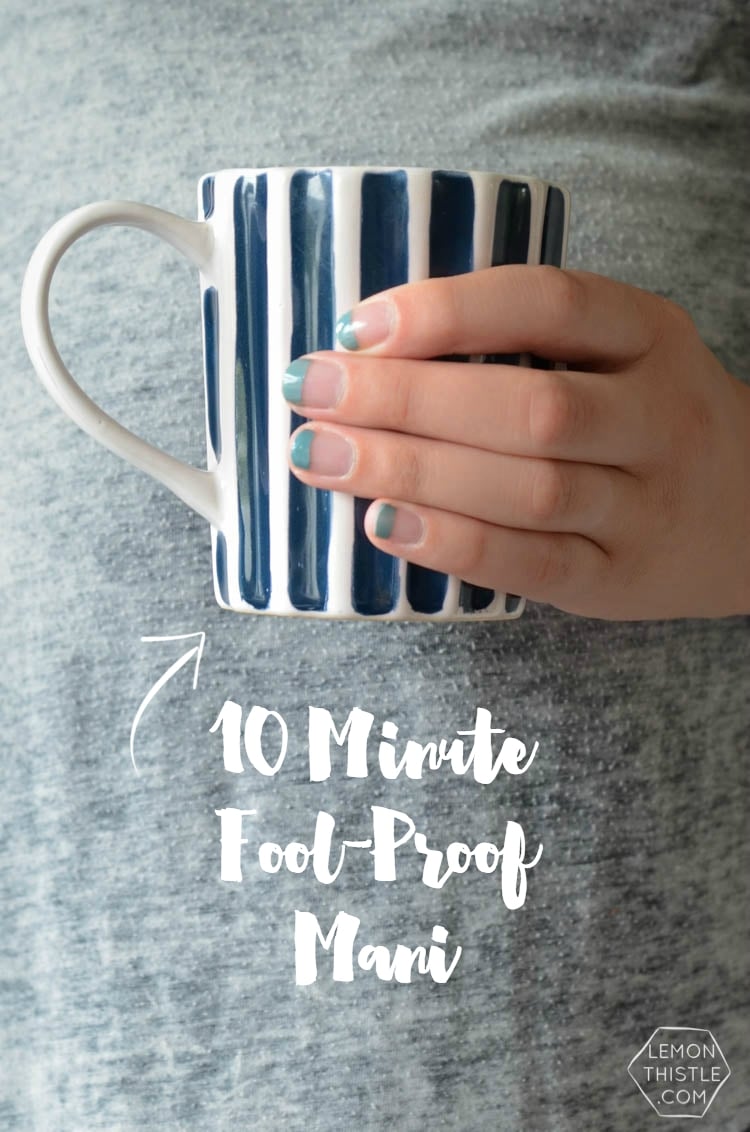Fool-Proof Taped Tip Manicure | Quick Nail Art Idea Hand holding a blue and white striped mug, showing a 10 minute taped tip manicure with teal polish on bare nails