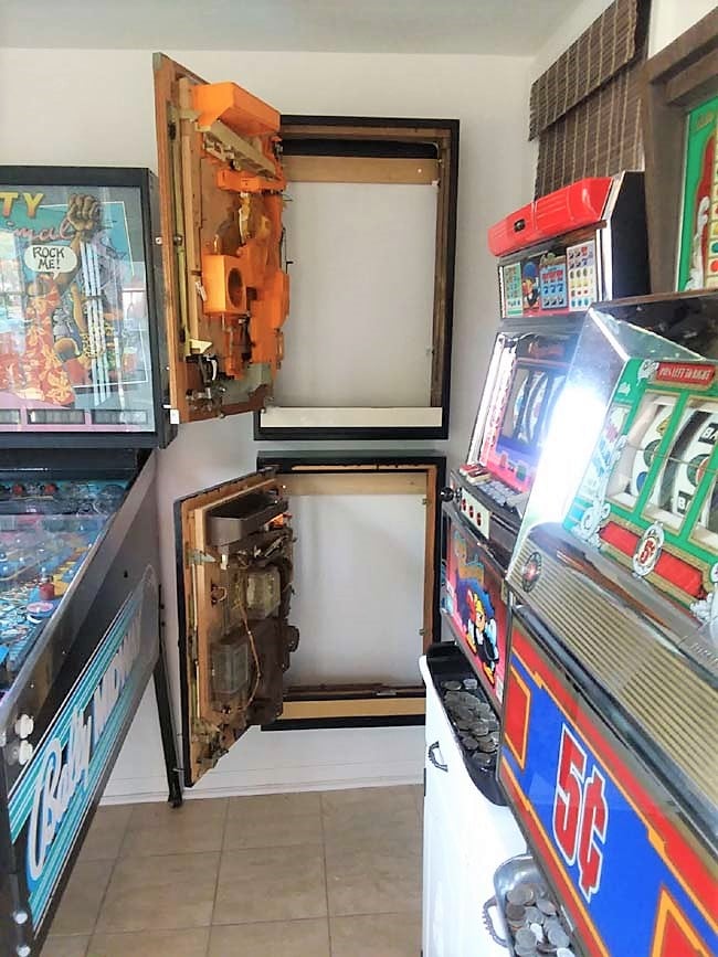 French Cleat Pachinko Cabinets | DIY Media Room Idea Two black wall cabinets with swing-out pachinko machine doors standing open beside a pinball machine and slot machines