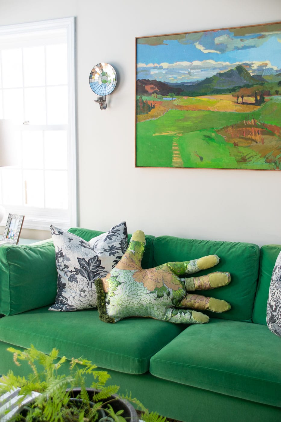 Quirky Giant Hand Pillow Sewing Gift Giant hand shaped pillow in green botanical print fabric with chartreuse nails lying on a green velvet sofa