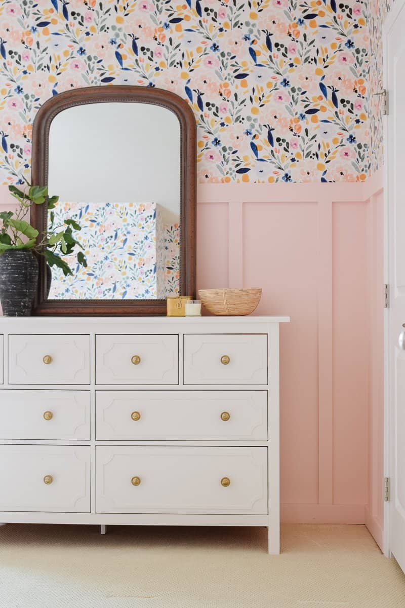 Hemnes Dresser Overlay Hack | IKEA Bedroom Hack White IKEA Hemnes eight-drawer dresser with overlay panels and brass knobs below a dark wood mirror and floral wallpaper