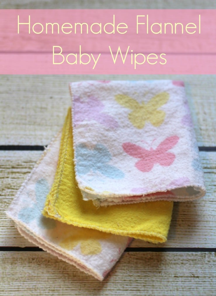 Stack of homemade flannel baby wipes in pink butterfly print and solid yellow with zigzag stitched edges on weathered wood