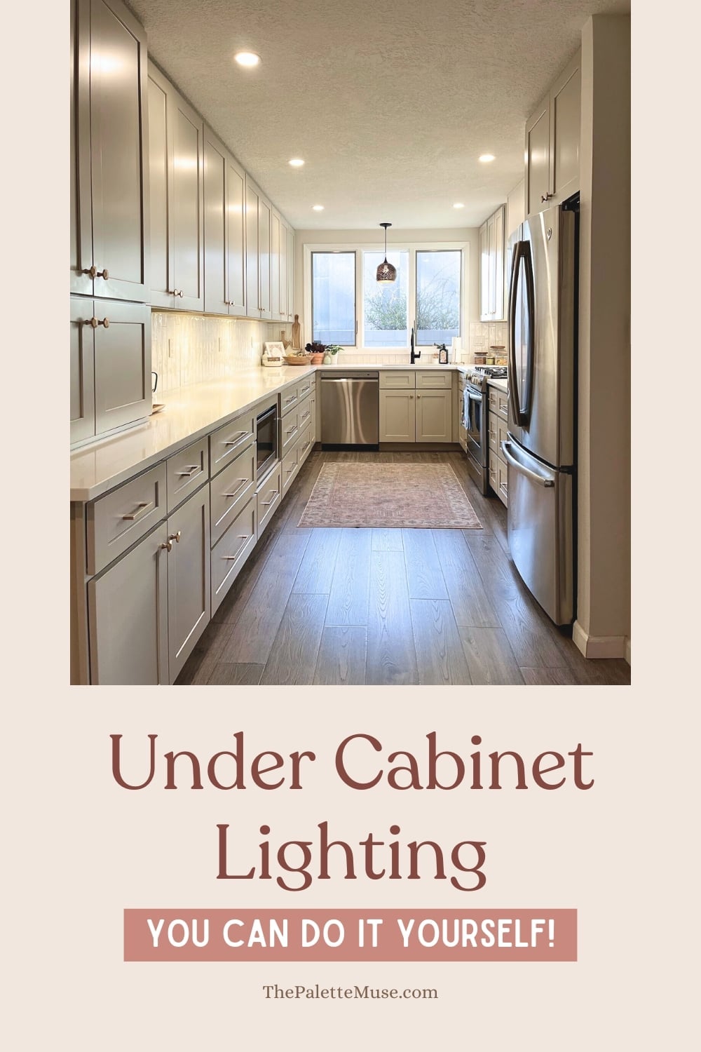 Long galley kitchen with gray painted cabinets glowing with warm under cabinet lights over white counters and a wood floor