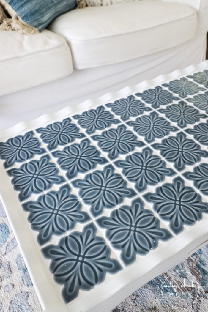 How to Tile a Table Top | Blue Tile Table Makeover How to tile a table top, a white painted table covered in navy and white embossed floral tiles in front of a white sofa