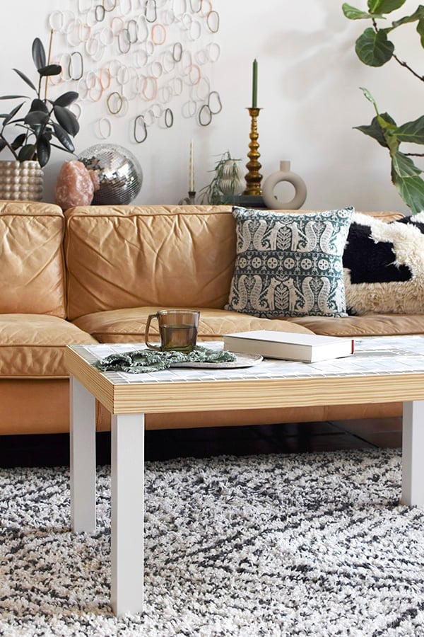 IKEA Hack Tiled Coffee Table | Geometric Mosaic Top IKEA hack coffee table with a white and pale green tile top, plywood edge and white legs in front of a tan leather sofa