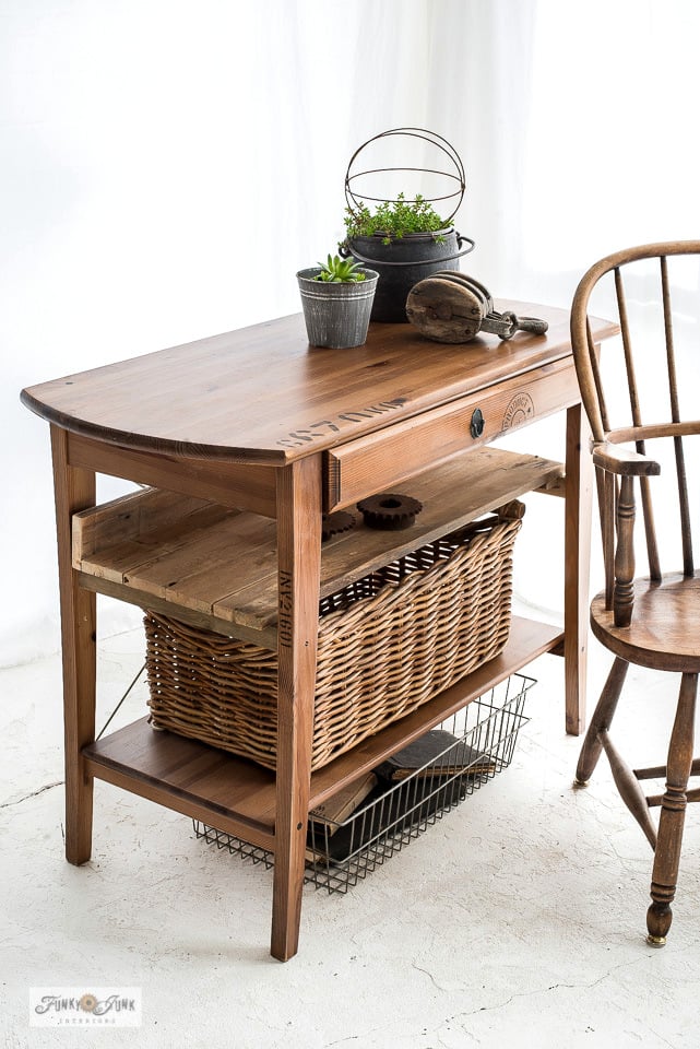 IKEA wood side table hacked with pallet style shelves holding a wicker basket and wire bin, next to a spindle back chair