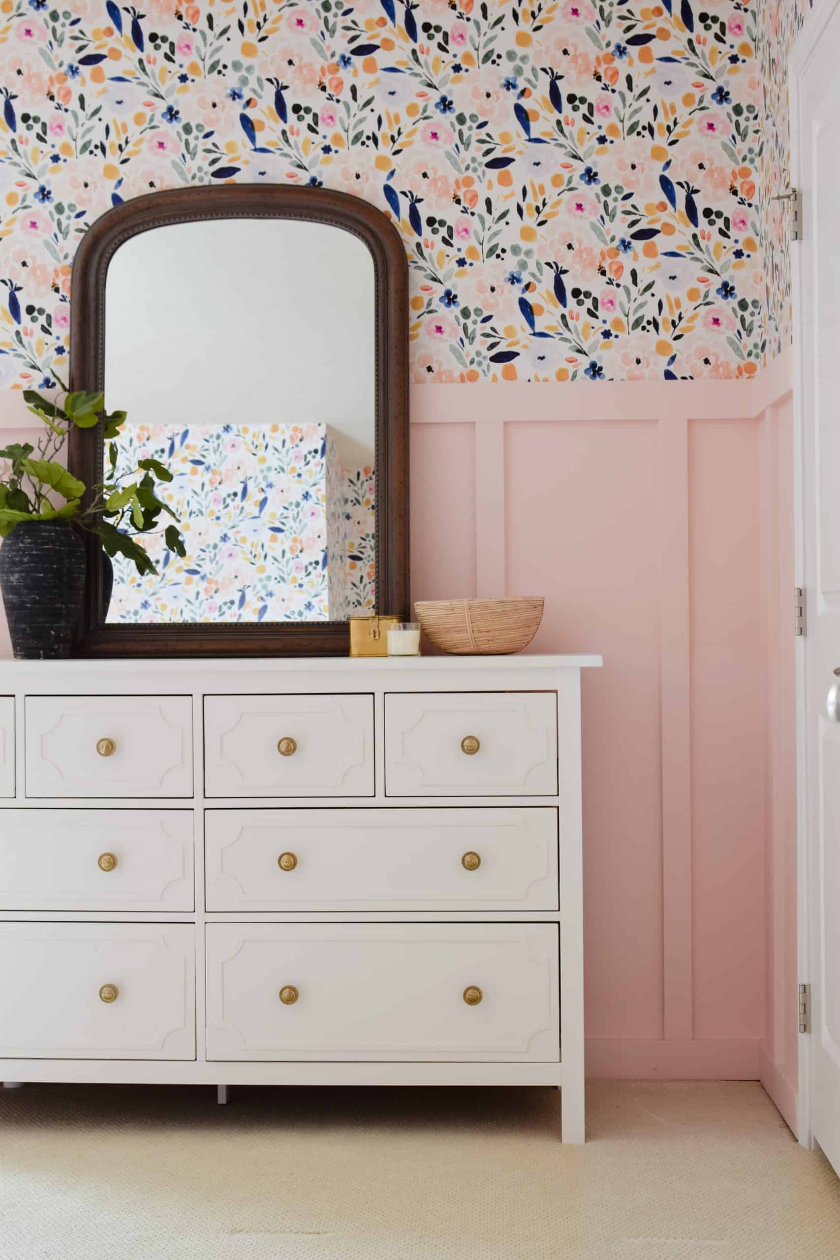 White IKEA Hemnes dresser with framed overlay panels and gold knobs against pink board and batten and floral wallpaper