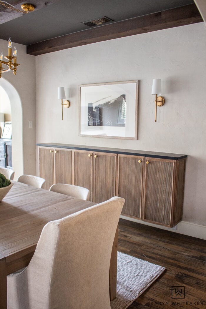 Floating wood buffet built from IKEA IVAR cabinets with fluted dowel doors, brass knobs and dark top in a dining room