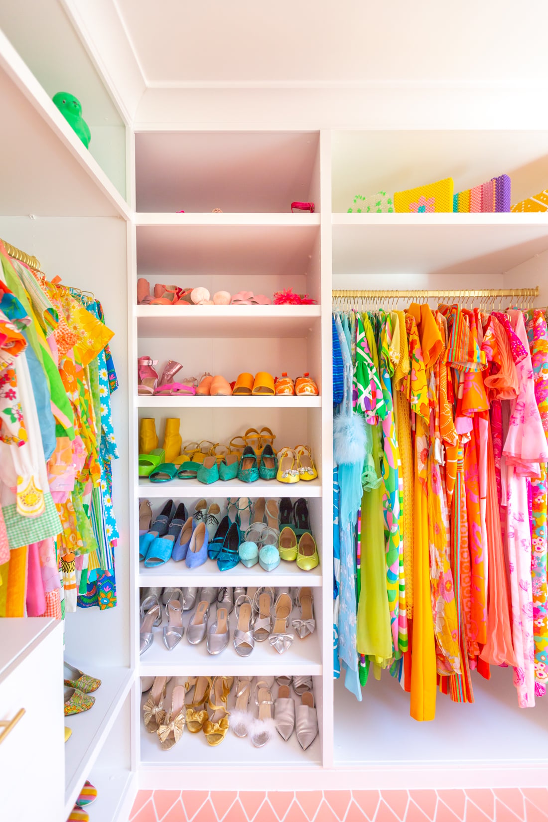 IKEA PAX Built-In Walk-In Closet | IKEA Bedroom Hack White IKEA PAX wardrobes trimmed into a built-in walk-in closet with shoes on shelves and colorful clothes on a gold rod