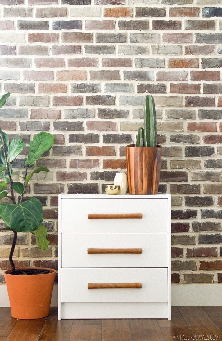 IKEA RAST Hack With Leather Pulls | IKEA Bedroom Hack White IKEA RAST three drawer dresser with leather wrapped dowel pulls set against a brick wall with a plant on top