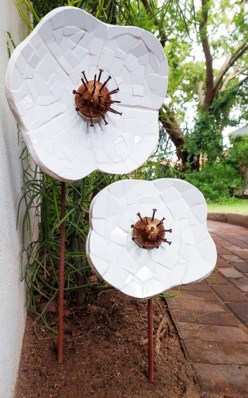 Large Mosaic Garden Flowers | Broken Tile Sculpture Large mosaic garden flowers in white broken tile on cement petals with rusty nail centers, standing on metal stems outdoors
