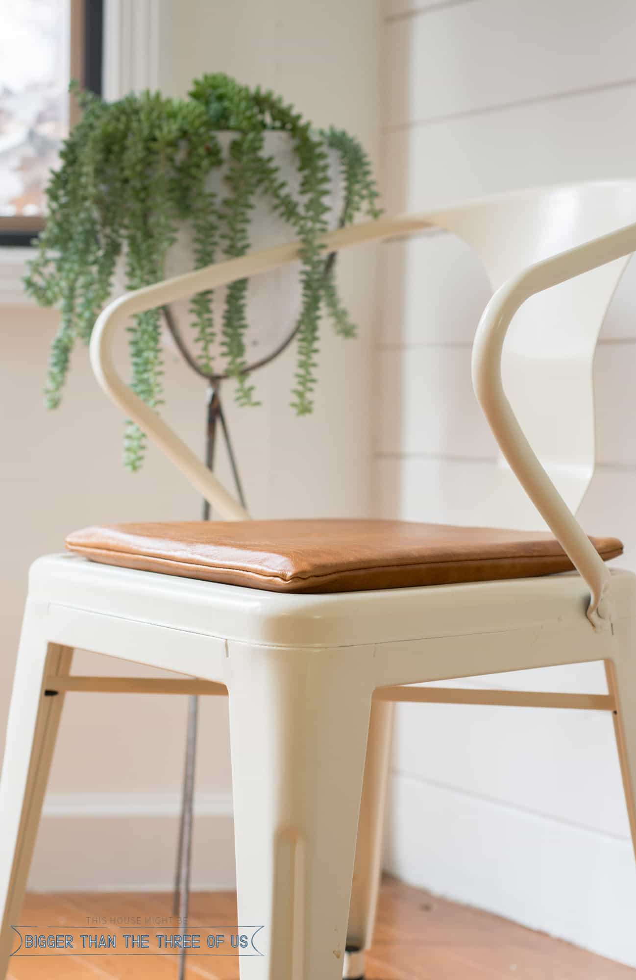 Leather Chair Cushion | Home Sewing Project Cream metal dining chair with a brown leather seat cushion beside a white shiplap wall and a trailing string of pearls plant