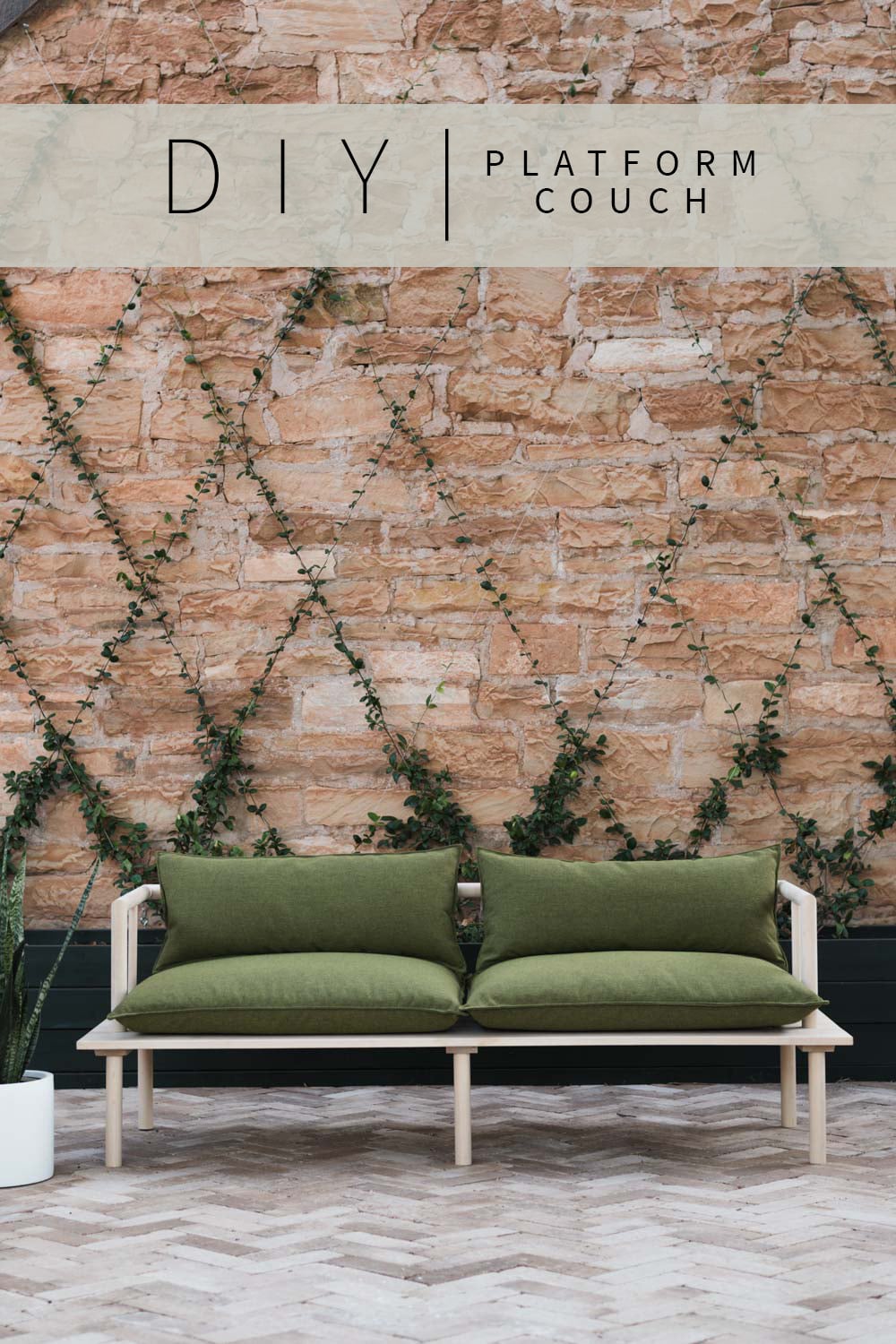 Modern Platform Outdoor Couch | DIY Patio Furniture Idea Light wood platform outdoor couch with olive green cushions on a herringbone brick patio in front of a vine covered wall