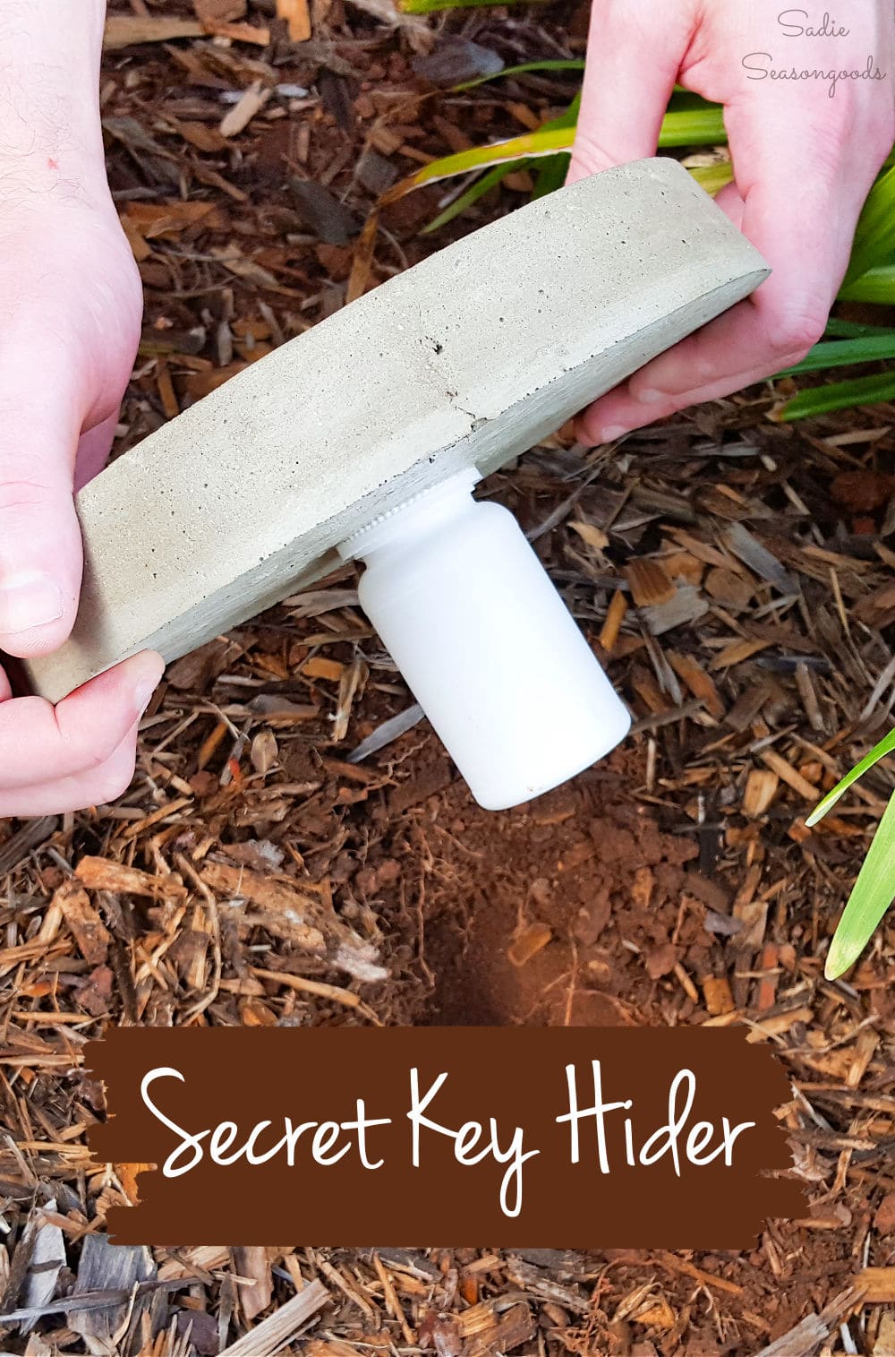 Mosaic Stepping Stone Key Hider | Garden DIY Hands lifting a round concrete stepping stone with a white pill bottle key holder set into its underside, over mulch