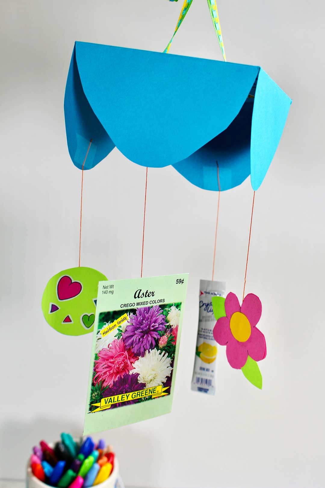 Mother's Day Card Mobile Mother's Day card mobile with a blue scalloped paper top and strings holding a seed packet, paper heart and paper flower