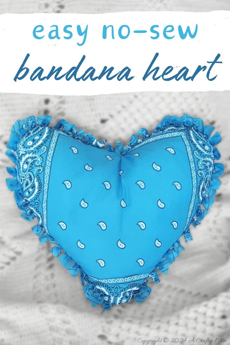 Blue paisley bandana heart pillow with woven fringe edges on a white knit throw, with easy no-sew bandana heart lettering