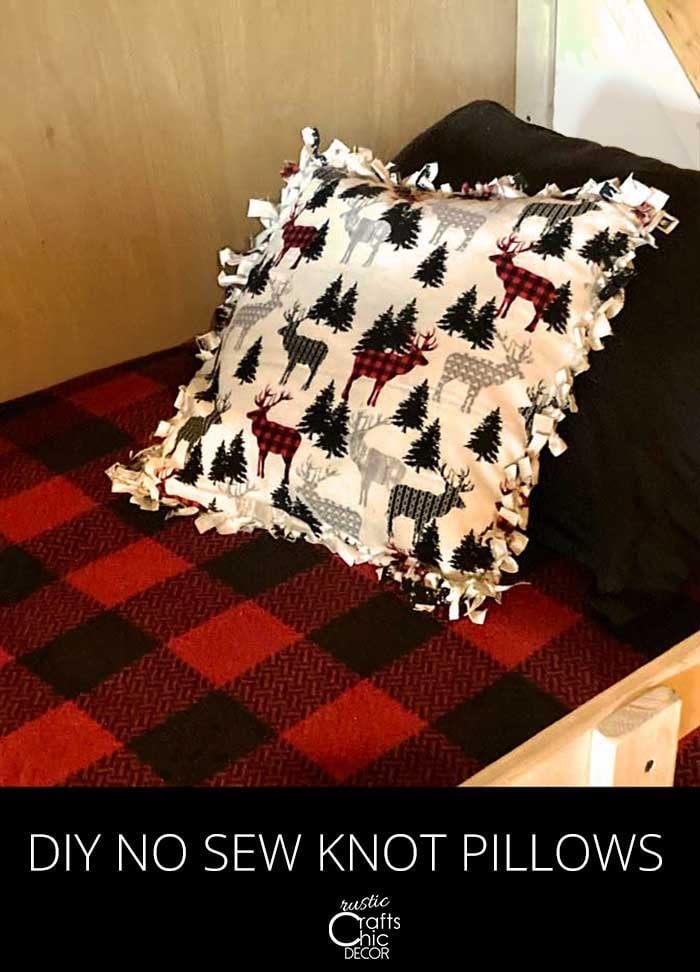 Square no-sew knot pillow in white fabric with plaid deer and trees and tied fringe edges on a buffalo check bed
