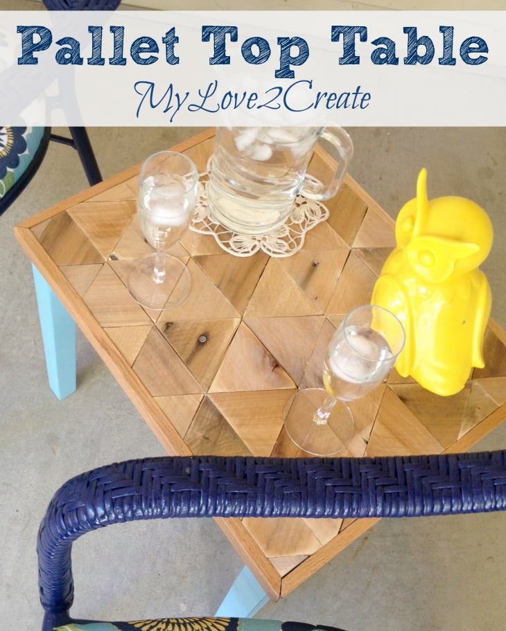 Small side table with a triangle pattern pallet wood top and aqua legs holding a pitcher, glasses and a yellow owl