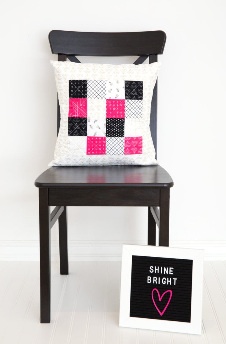 Patchwork Quilted Pillow | Home Sewing Project Patchwork quilted pillow in pink, black and white squares on a black wood chair beside a Shine Bright letter board
