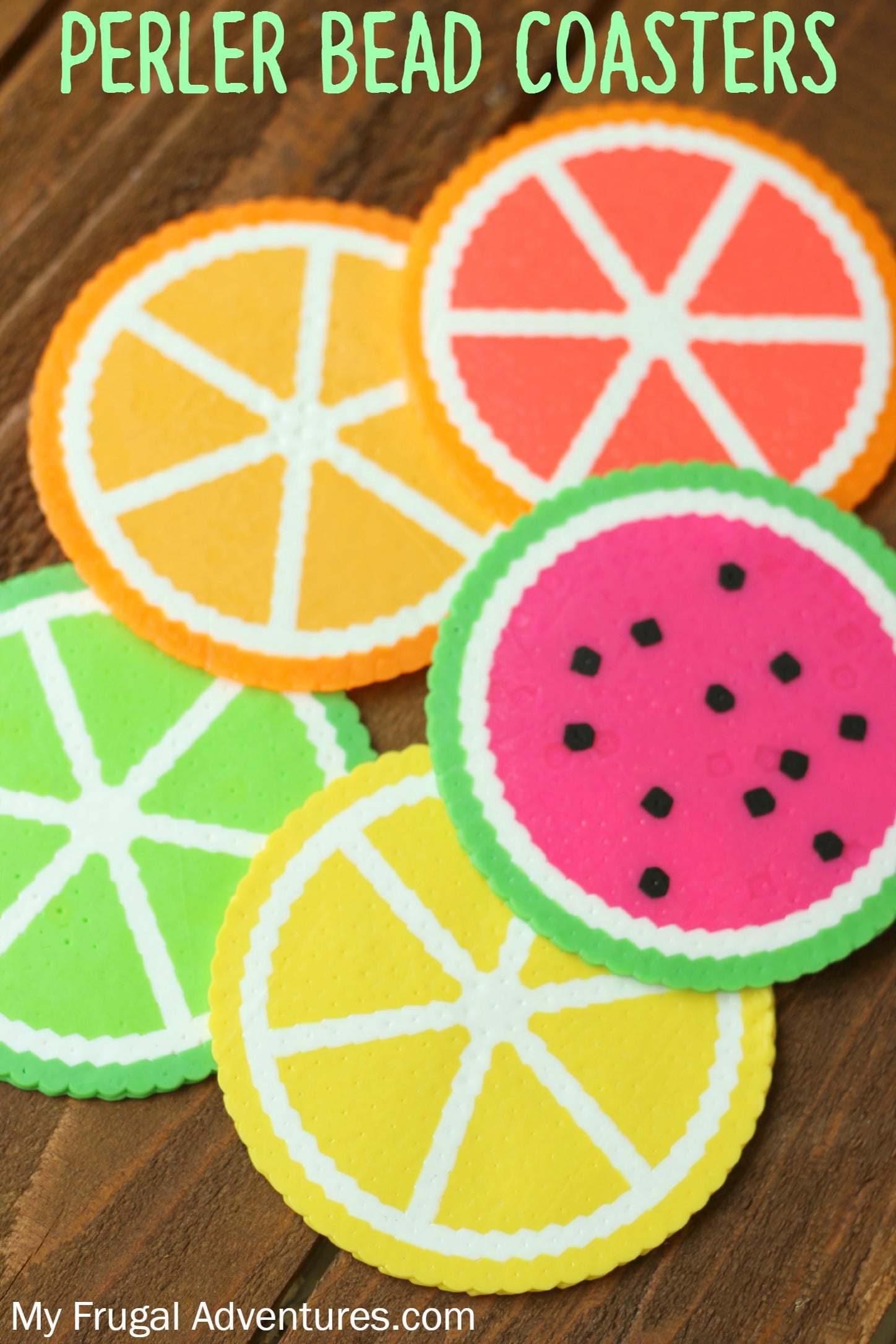 Five perler bead coasters made as lemon, lime, orange and watermelon slices, overlapping on a dark wooden table