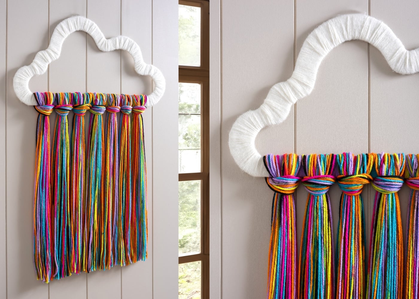 Two views of a white yarn wrapped cloud with long rainbow yarn fringe hanging below it on a white paneled wall