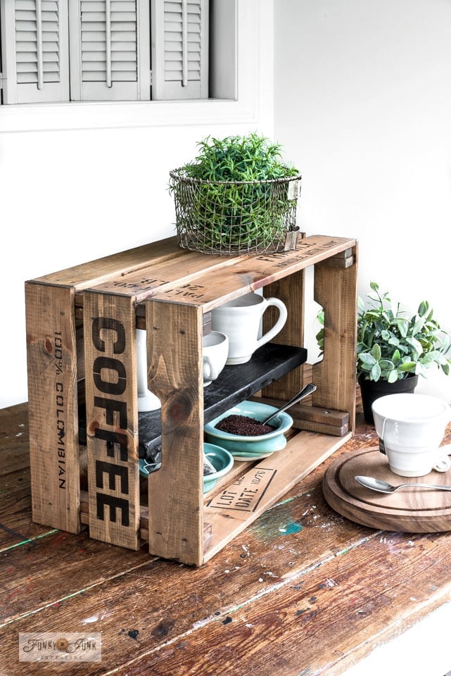 Rustic IKEA wood crate coffee station with a stenciled COFFEE side, white mugs and a wire basket of greens on top
