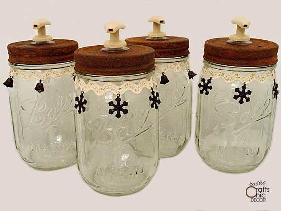 Four clear mason jar soap dispensers with rusty brown lids, lace trim, black snowflake charms and little cream pumps