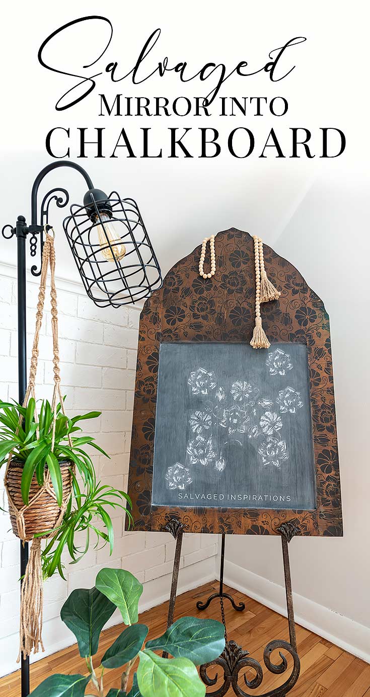Arched salvaged mirror frame stenciled with dark florals and made into a chalkboard, draped with a wood bead tassel garland