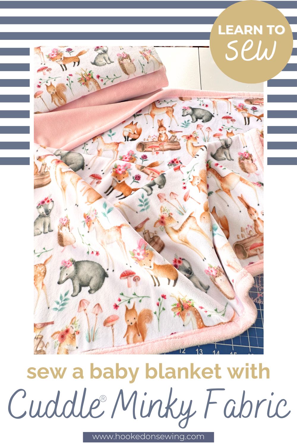 Folded baby blanket in a woodland fox and deer print minky with a blush pink minky back and binding on a cutting mat