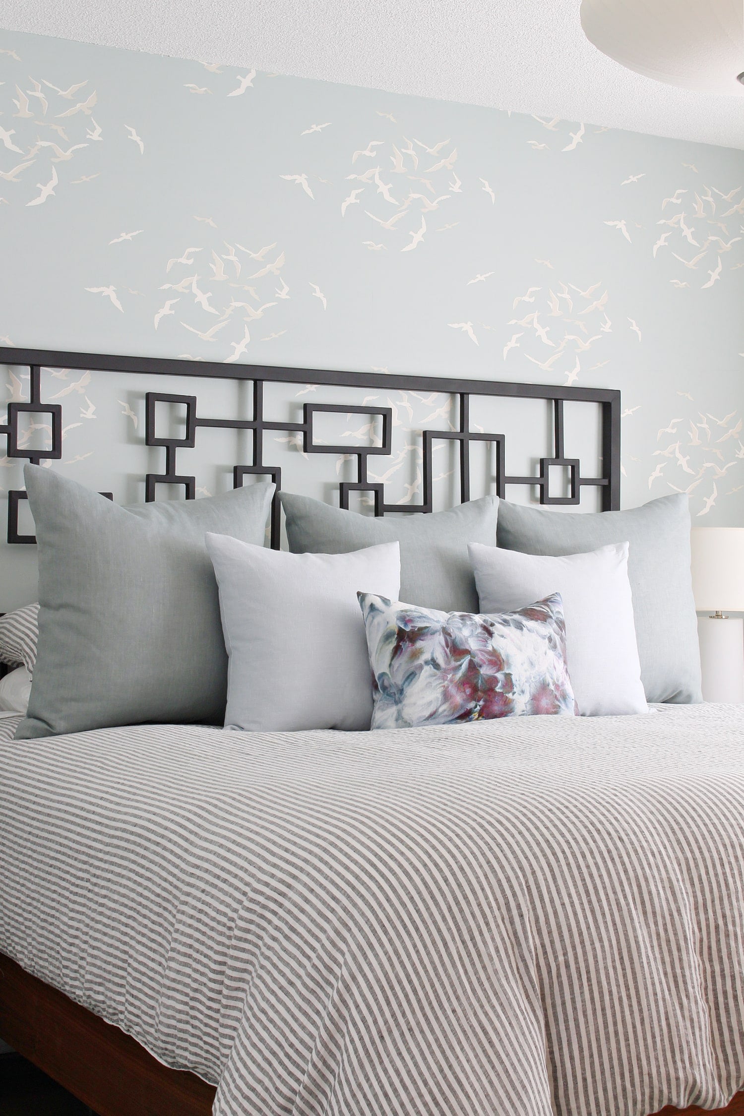 Sew Euro Pillow Shams | Home Sewing Project Bed with gray blue linen Euro shams, white and floral throw pillows, striped duvet and a black geometric headboard