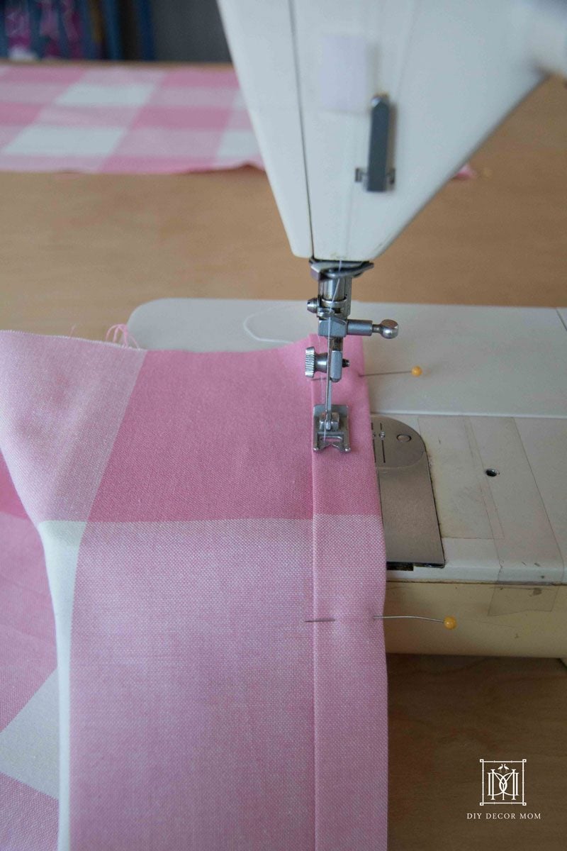 DIY Crib Skirt | Custom Crib Bed Skirt Tutorial DIY crib skirt in a pink nursery, a white crib with a pink skirt beside a kelly green dresser and a colorful pom garland