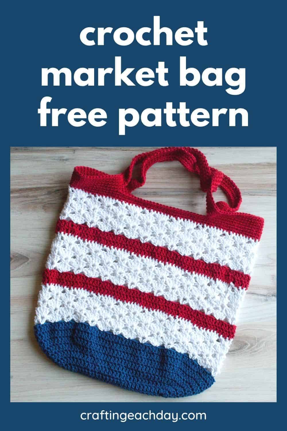 Crochet market bag in red, white and navy stripes with white shell stitch bands and red handles, laid flat on a wood floor