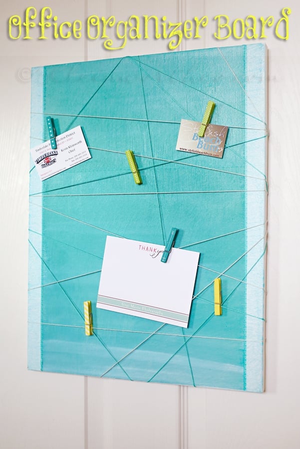 Turquoise canvas organizer board strung with crisscrossed embroidery floss holding a card and notes with yellow clothespins