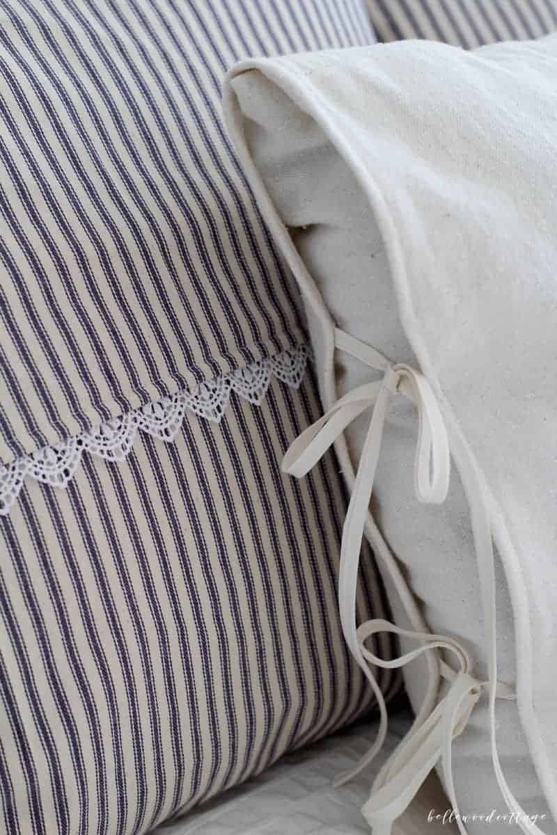 Ticking stripe pillow covers, navy and cream striped cover with a white lace trim beside a cream pillow