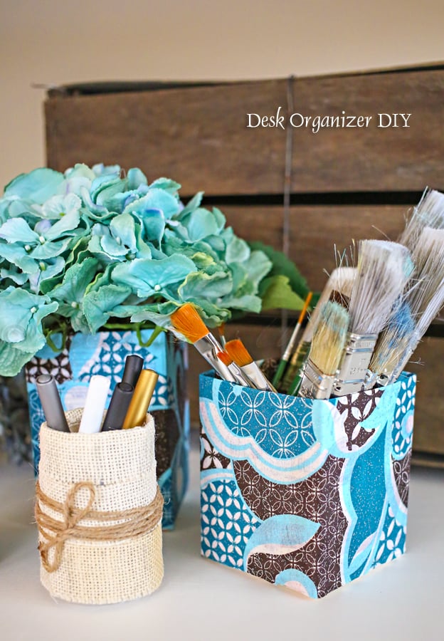 Upcycled bottles wrapped in burlap and twine and cartons covered in blue patterned fabric holding paint brushes and pens
