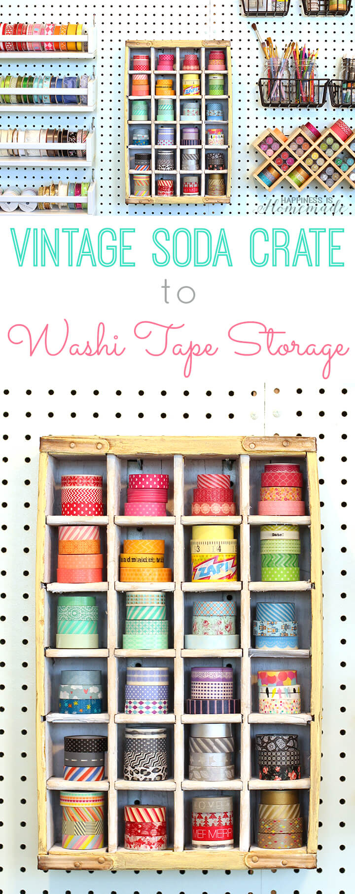 Yellow vintage wooden soda crate hung on a white pegboard wall, each small cubby holding a colorful roll of washi tape